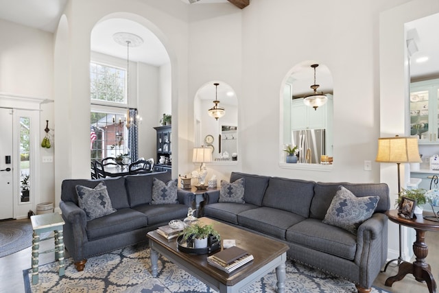 living area featuring arched walkways, a high ceiling, and wood finished floors