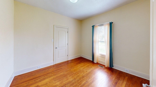 spare room with light wood-type flooring, baseboards, and visible vents