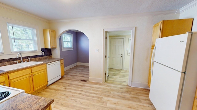 kitchen with a sink, arched walkways, white appliances, and crown molding