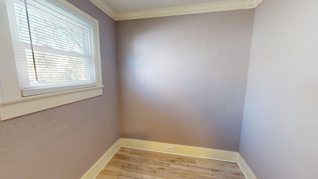 empty room with baseboards, crown molding, and wood finished floors