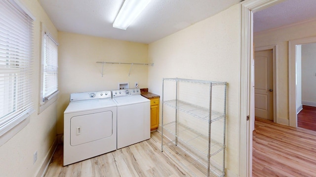 washroom featuring cabinet space, independent washer and dryer, light wood finished floors, and baseboards