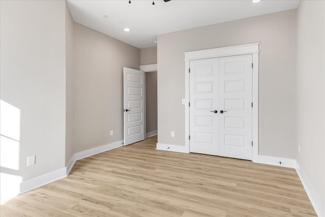 unfurnished bedroom featuring a closet, light wood-style flooring, recessed lighting, and baseboards