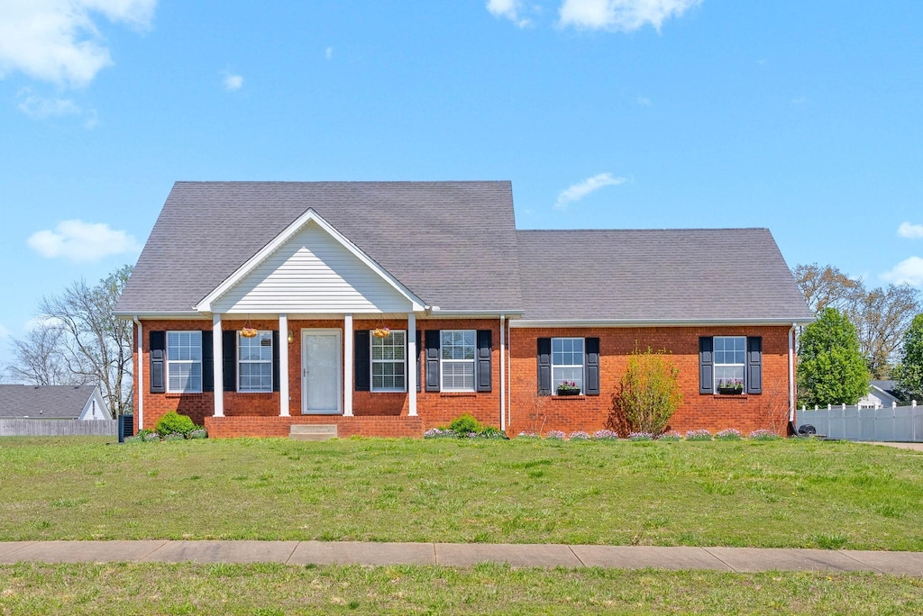 view of front of home with a front yard, brick siding, and fence