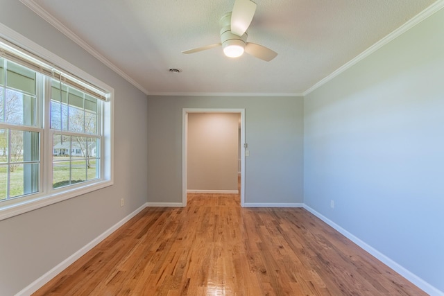 unfurnished room with baseboards, a ceiling fan, a textured ceiling, crown molding, and light wood finished floors