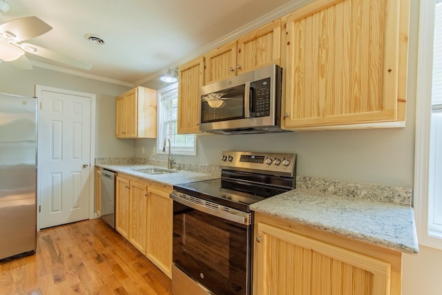 kitchen with appliances with stainless steel finishes, light brown cabinets, ornamental molding, ceiling fan, and a sink