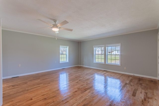 spare room featuring light wood-style floors, crown molding, baseboards, and a ceiling fan