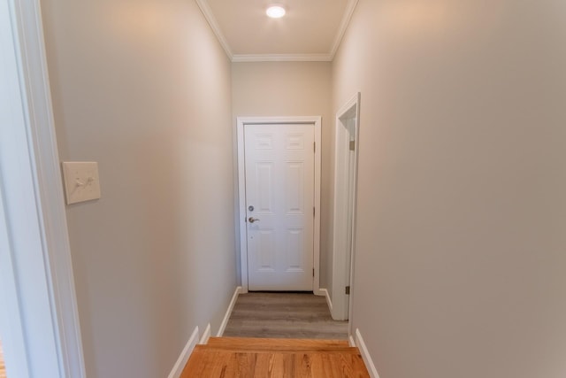 hallway featuring light wood-style flooring, crown molding, and baseboards