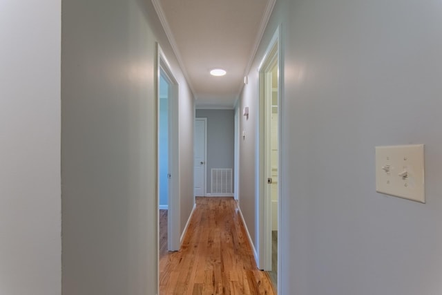 corridor featuring crown molding, baseboards, visible vents, and light wood-type flooring