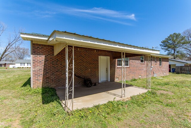rear view of house featuring a patio, a yard, metal roof, and brick siding