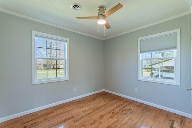 empty room featuring ornamental molding, light wood-style flooring, a ceiling fan, and baseboards