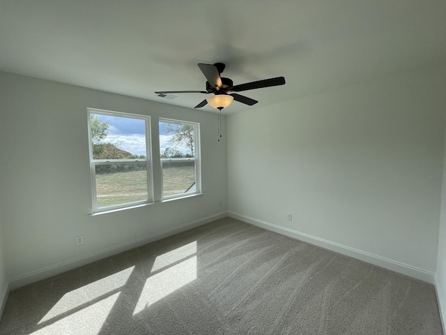 carpeted empty room featuring baseboards, a ceiling fan, and visible vents