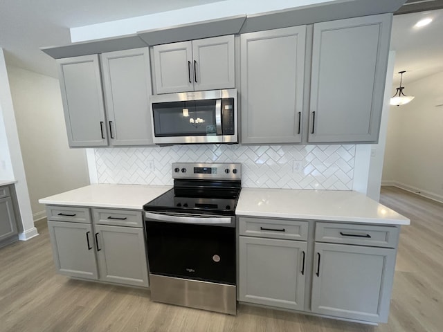 kitchen with gray cabinets, light wood-type flooring, and appliances with stainless steel finishes