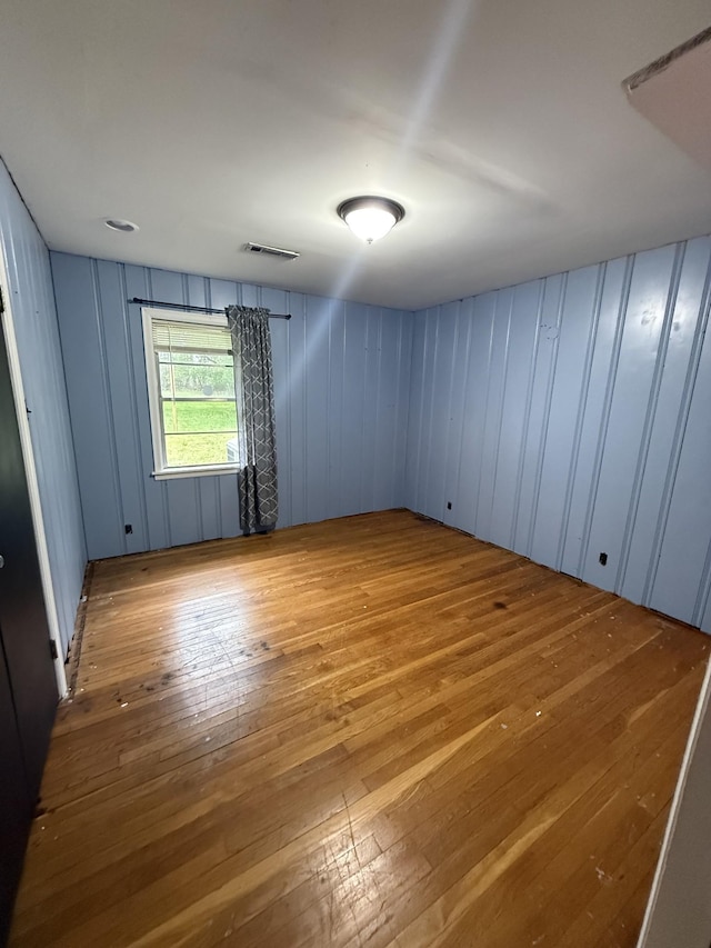 unfurnished room featuring visible vents and hardwood / wood-style floors