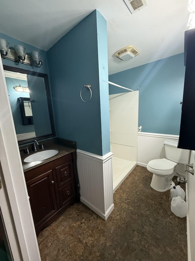 full bath with vanity, toilet, a walk in shower, wainscoting, and visible vents