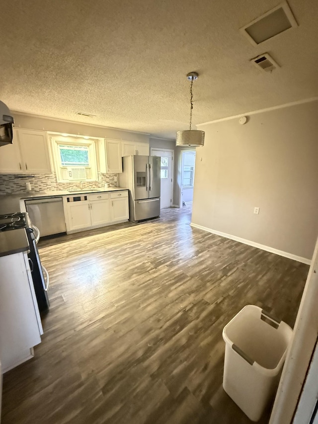 kitchen featuring dark wood finished floors, white cabinets, visible vents, decorative backsplash, and stainless steel appliances