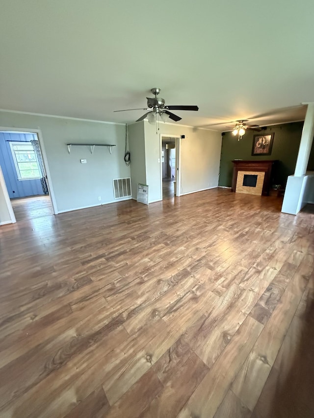 unfurnished living room featuring a fireplace, visible vents, a ceiling fan, and wood finished floors