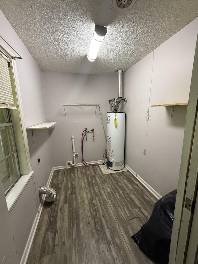 washroom with laundry area, a textured ceiling, gas water heater, wood finished floors, and baseboards