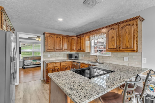 211 Northview Ct, Hendersonville, TN 37075 - kitchen featuring stainless steel appliances, a sink, a peninsula, brown cabinets, and light wood-style floors