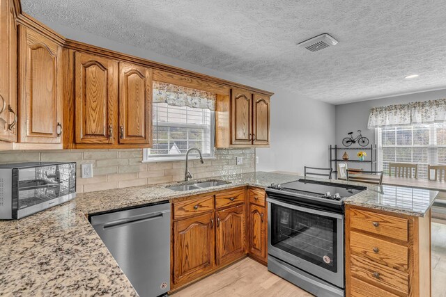 211 Northview Ct, Hendersonville, TN 37075 - kitchen with stainless steel appliances, a sink, a peninsula, brown cabinets, and a textured ceiling
