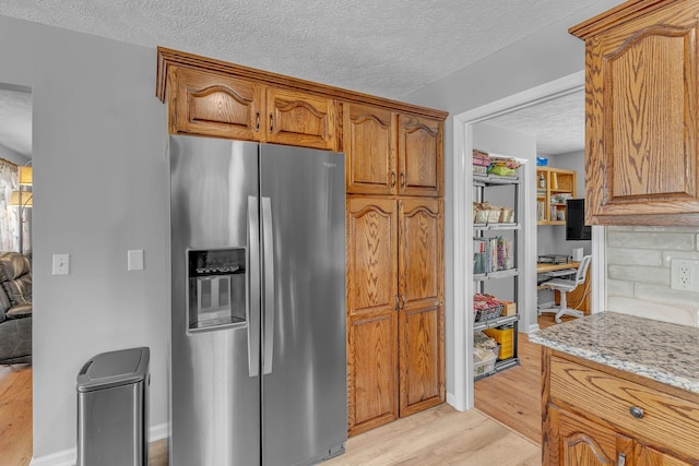 211 Northview Ct, Hendersonville, TN 37075 - kitchen with stainless steel fridge, light wood-style floors, a textured ceiling, light stone counters, and brown cabinets