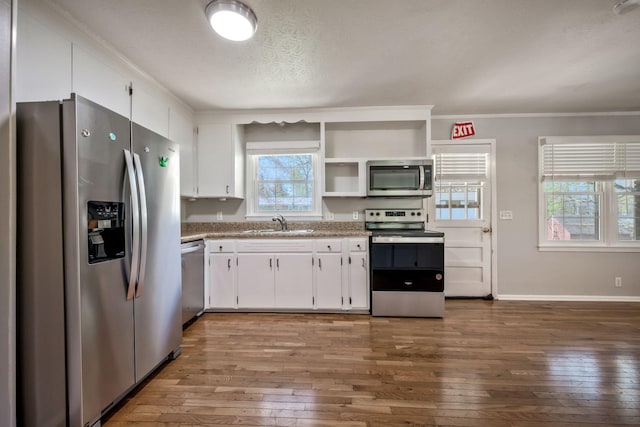 kitchen featuring appliances with stainless steel finishes, a sink, white cabinetry, and hardwood / wood-style flooring