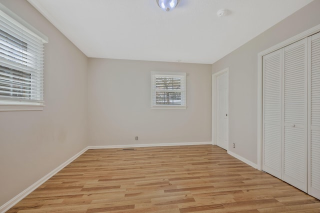 unfurnished bedroom featuring a closet, light wood finished floors, and baseboards