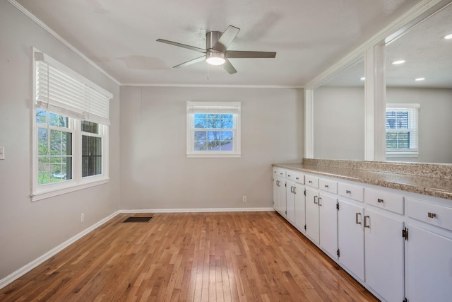 empty room featuring visible vents, baseboards, ornamental molding, ceiling fan, and light wood-style flooring