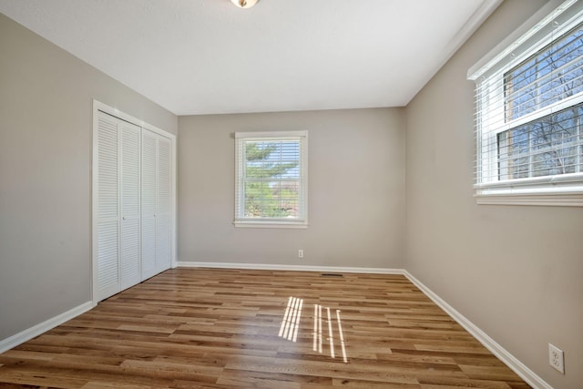 unfurnished bedroom with a closet, baseboards, and wood finished floors