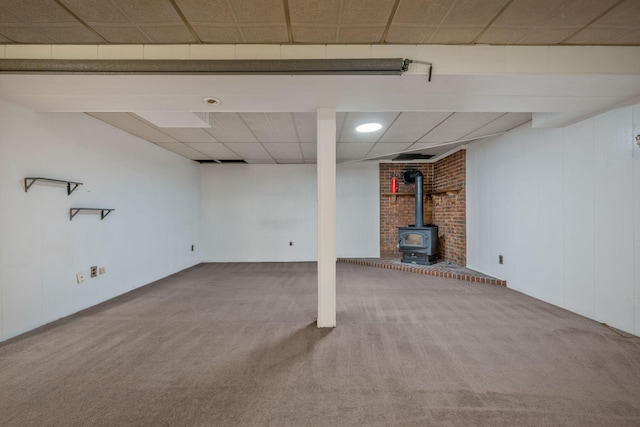 finished below grade area with a wood stove, carpet, and a paneled ceiling