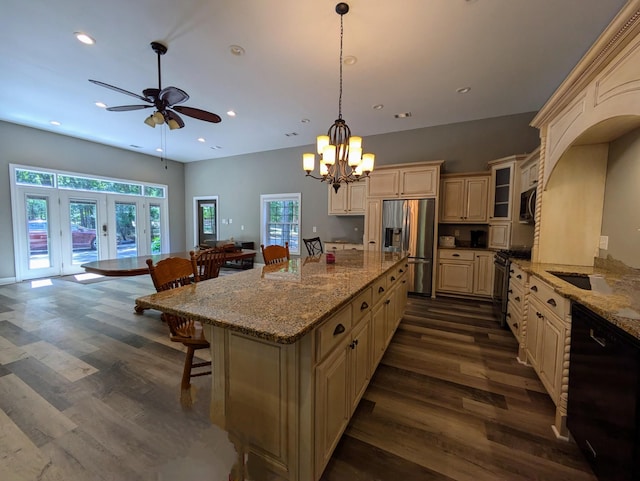 kitchen featuring cream cabinetry, ceiling fan with notable chandelier, dark wood-type flooring, a breakfast bar area, and stainless steel appliances