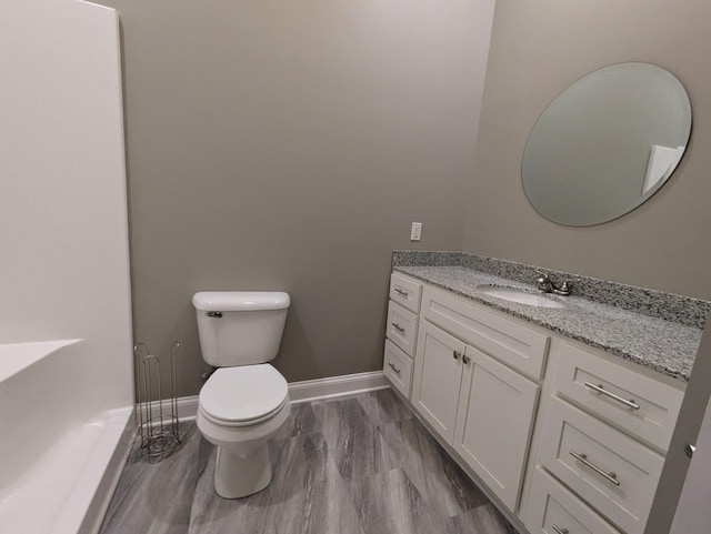 bathroom featuring toilet, vanity, and baseboards