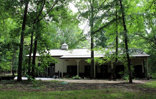 back of house featuring board and batten siding and metal roof