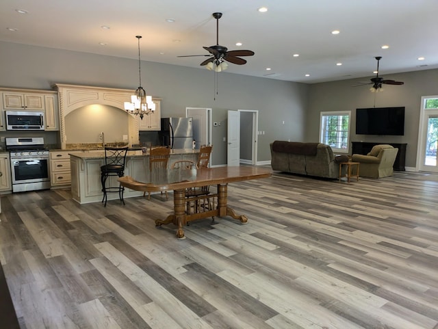 dining area with ceiling fan with notable chandelier, wood finished floors, baseboards, and recessed lighting