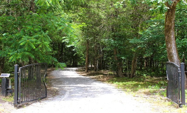 view of street featuring a view of trees, a gated entry, and a gate