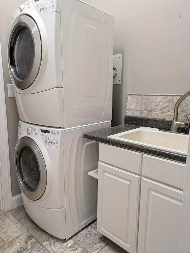 washroom featuring stacked washer and dryer, a sink, and cabinet space