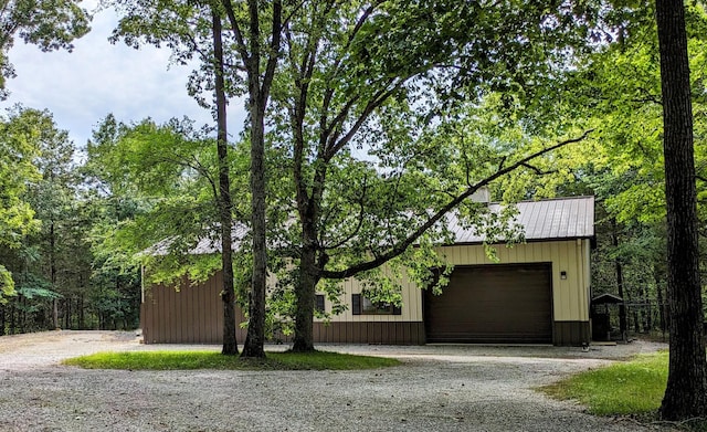 exterior space featuring an attached garage, metal roof, and gravel driveway