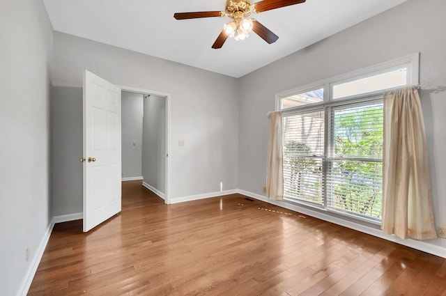 unfurnished room featuring light wood finished floors, baseboards, and a ceiling fan