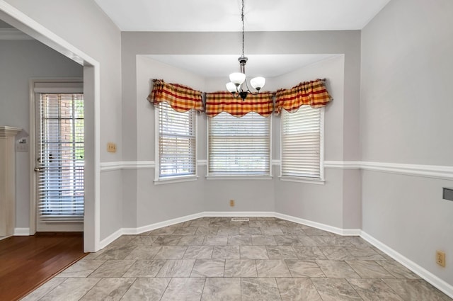 unfurnished dining area featuring a chandelier, baseboards, and plenty of natural light