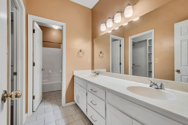 full bath featuring tile patterned floors, double vanity, baseboards, and a sink