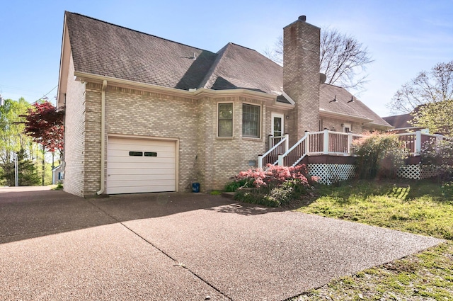 english style home featuring brick siding, roof with shingles, driveway, and a chimney