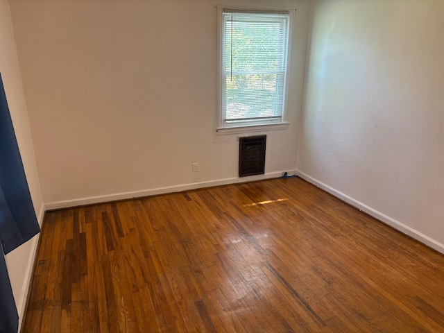 spare room featuring visible vents, hardwood / wood-style flooring, and baseboards