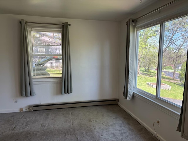 carpeted spare room with plenty of natural light, a baseboard heating unit, and baseboards