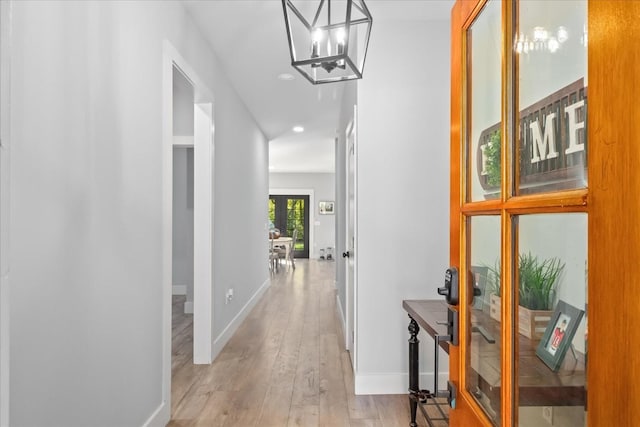 hall with a chandelier, recessed lighting, light wood-style flooring, and baseboards
