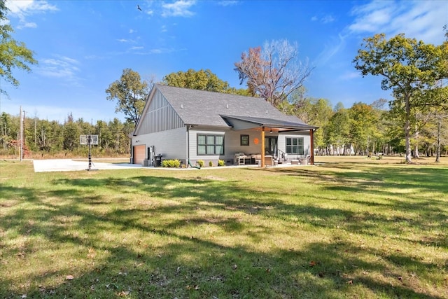 back of house featuring a yard, an attached garage, and board and batten siding