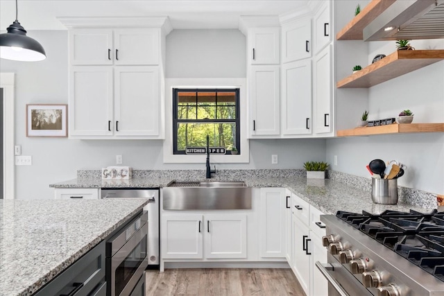 kitchen featuring light wood-type flooring, open shelves, white cabinets, a sink, and stainless steel appliances