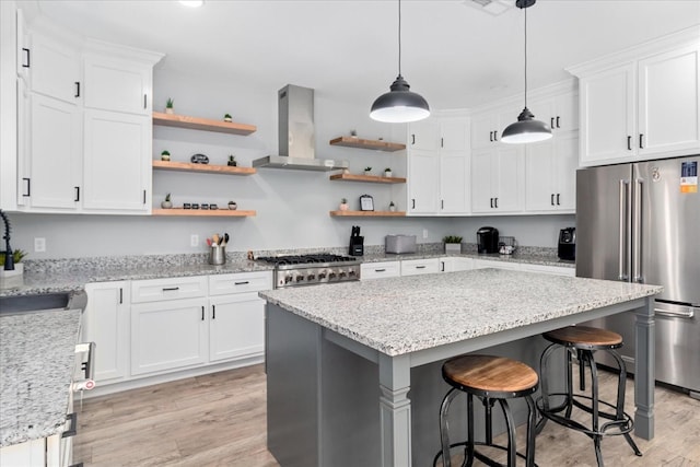 kitchen with high end refrigerator, open shelves, light wood-style floors, and wall chimney range hood