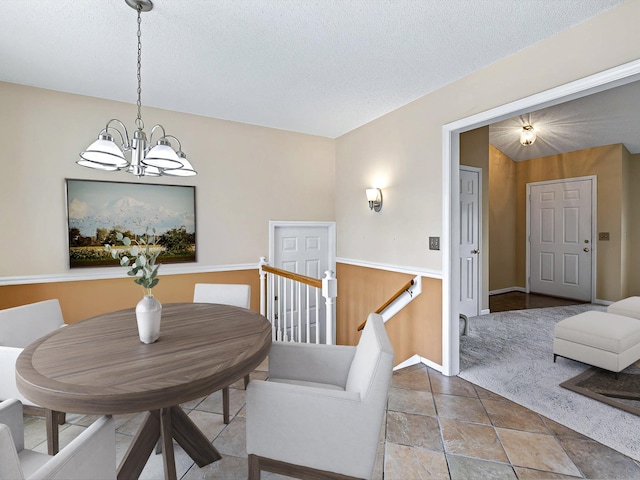 dining area featuring a notable chandelier, a textured ceiling, and baseboards