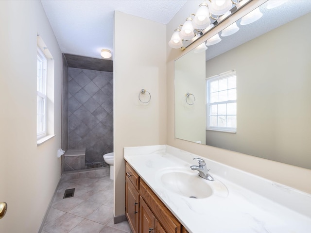 bathroom featuring visible vents, toilet, vanity, tiled shower, and tile patterned flooring