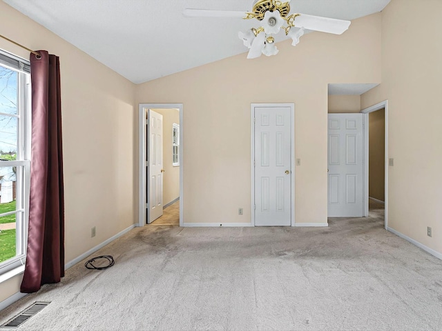 unfurnished bedroom with visible vents, multiple windows, vaulted ceiling, and carpet floors