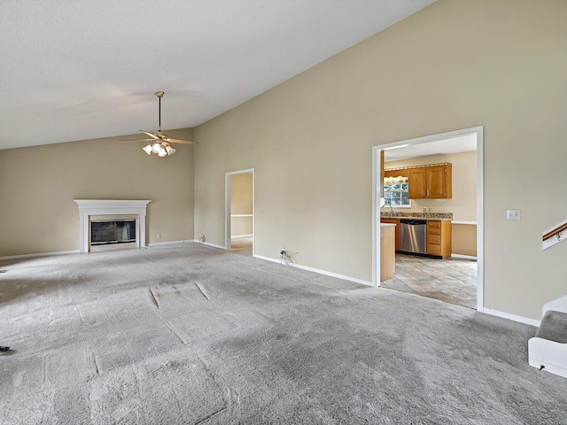 unfurnished living room featuring a glass covered fireplace, ceiling fan, light colored carpet, and baseboards